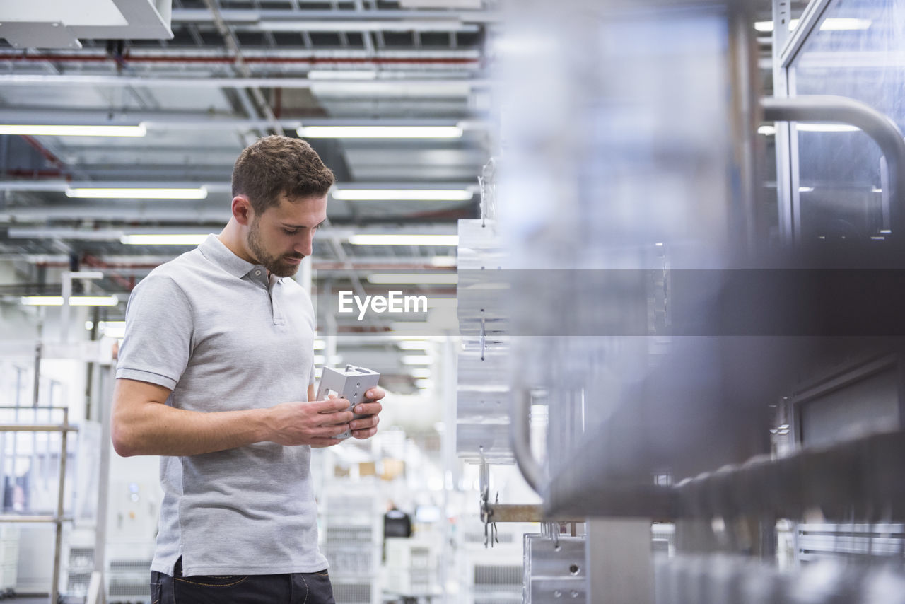 Man with tablet in factory shop floor examining products
