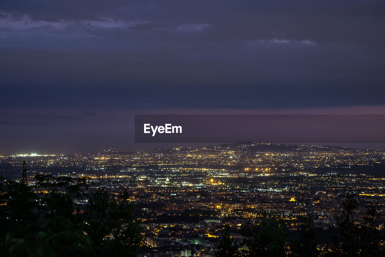 Illuminated cityscape against sky at night
