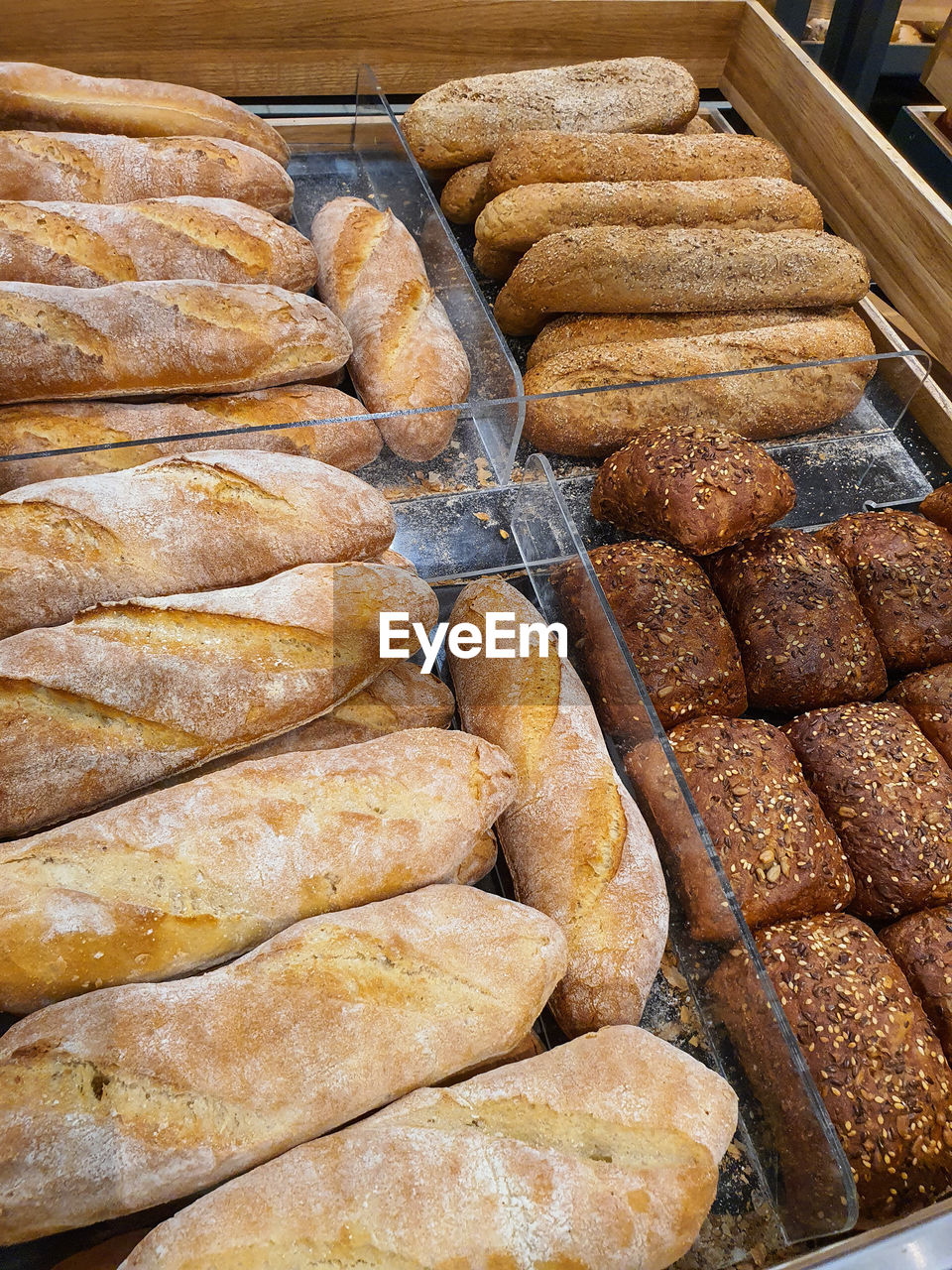 Variety of different types of bread, baguettes and hot dog buns in a bakery or grocery store