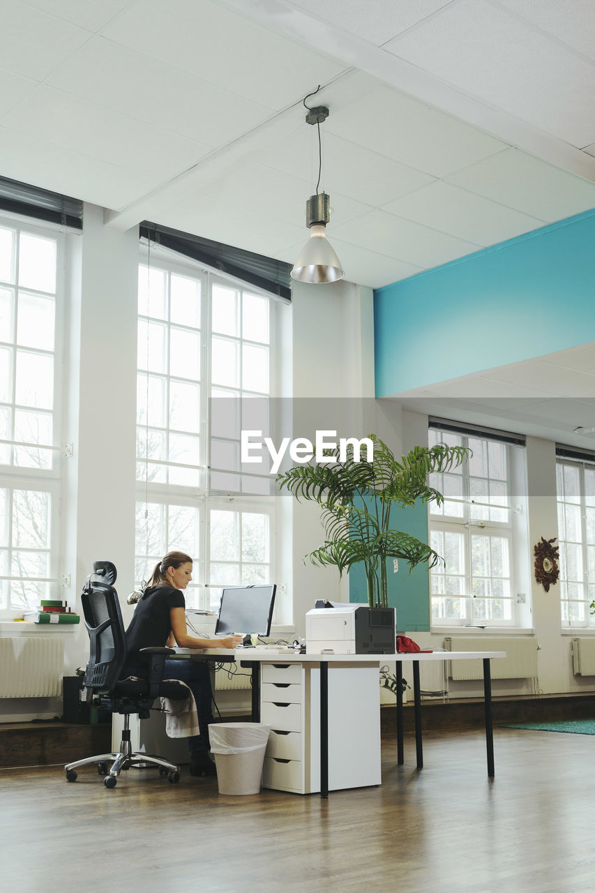 Businesswoman working at computer desk in creative workspace