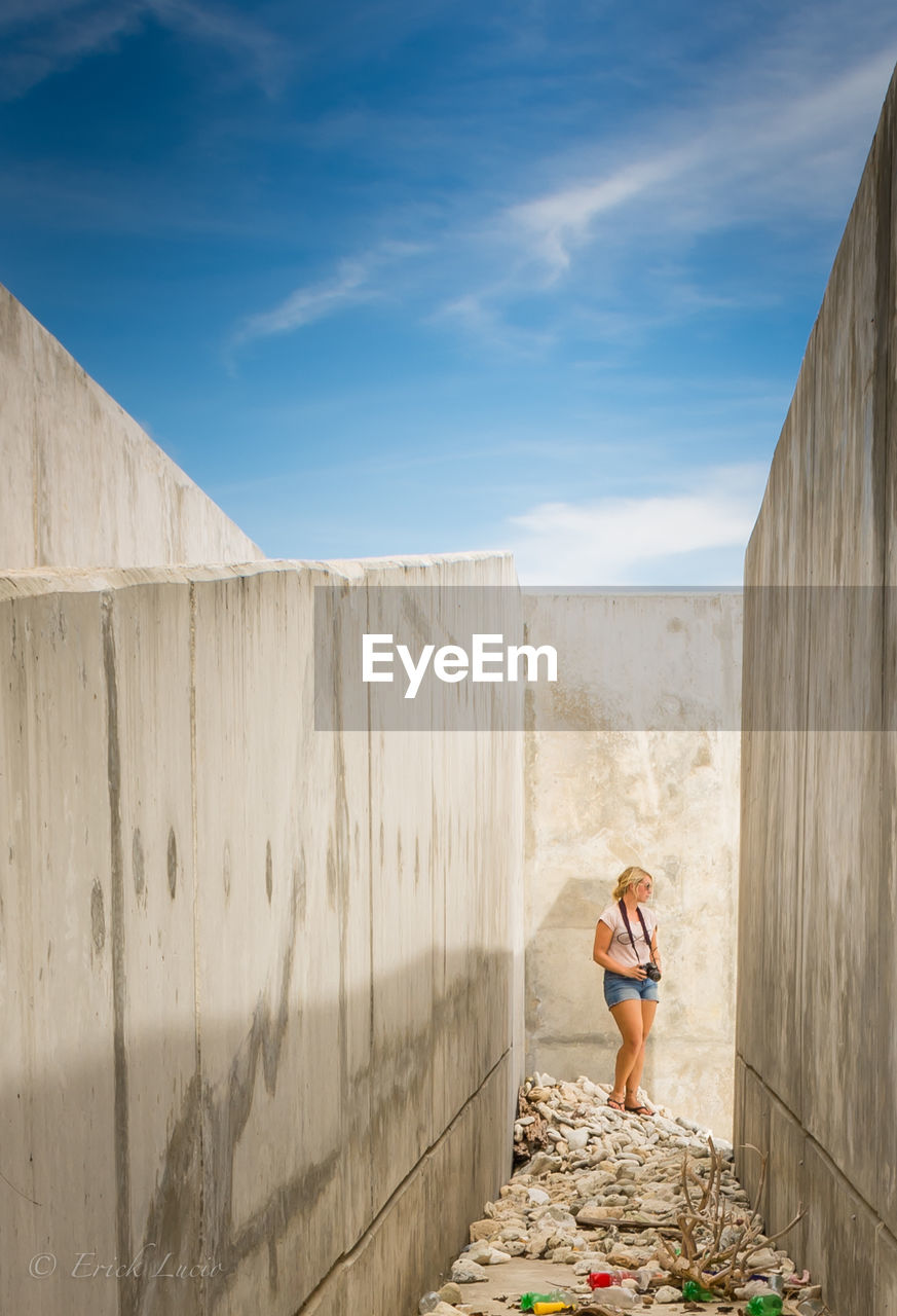 Young woman standing amidst concrete wall