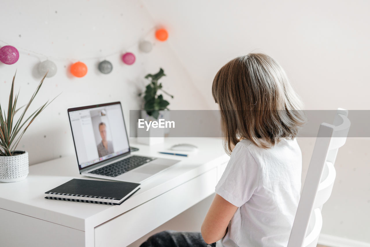 A teenage girl is talking to her dad or friend using a laptop. online communications. 