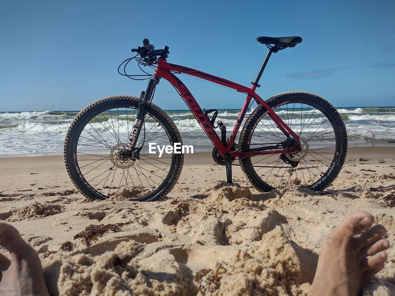 beach, land, bicycle, sea, sand, water, nature, transportation, sky, vehicle, sports equipment, mountain bike, sunlight, activity, leisure activity, mode of transportation, sports, holiday, travel, land vehicle, road bicycle, trip, horizon over water, vacation, clear sky, horizon, day, motion, wheel, beauty in nature, one person, lifestyles, outdoors, bicycle wheel, shadow, sunny, mountain biking, scenics - nature, travel destinations, summer, relaxation, cycling, racing bicycle, coast, tranquility, adult, blue, tire