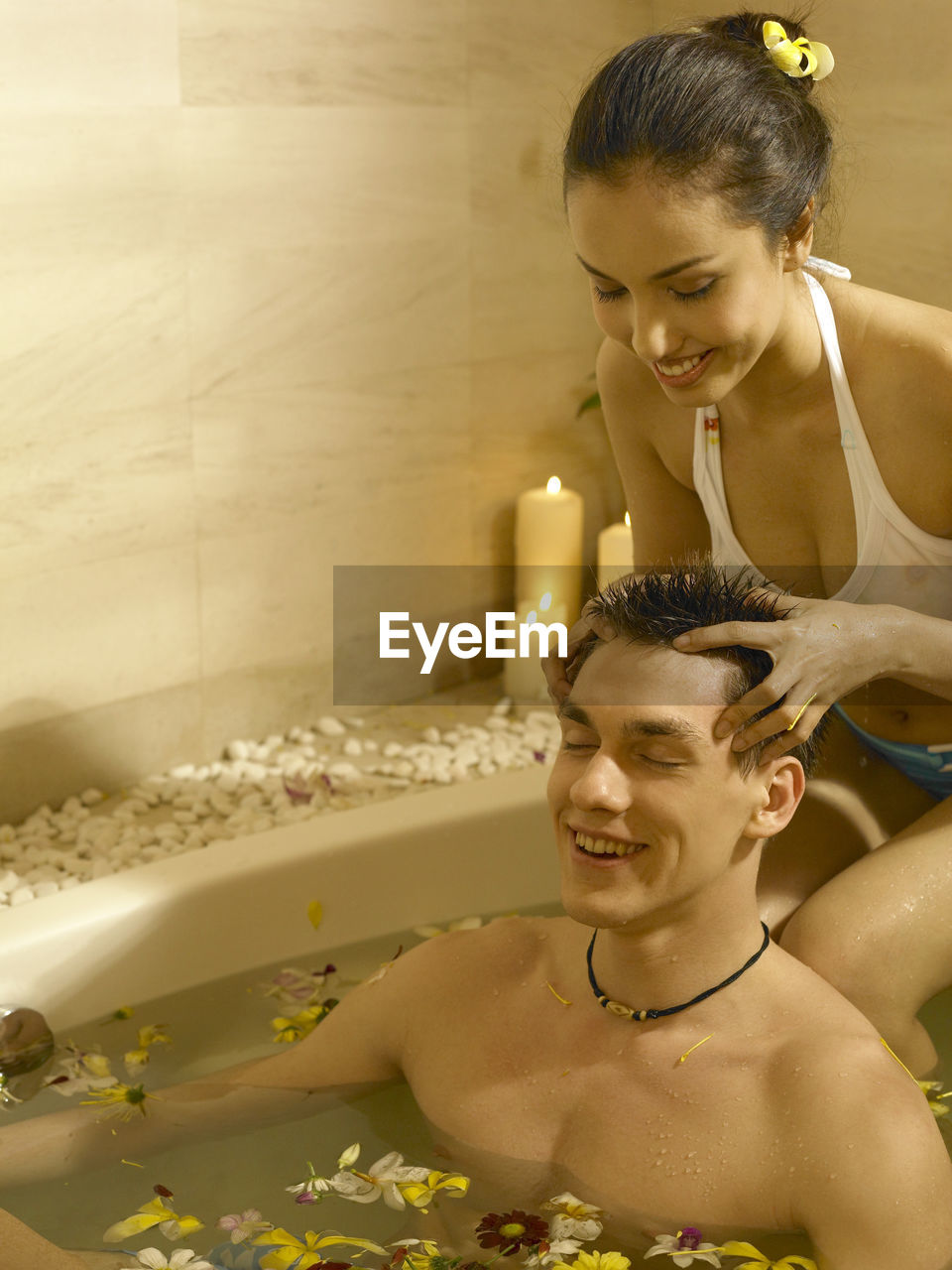 Girlfriend giving head massage to boyfriend in bathtub