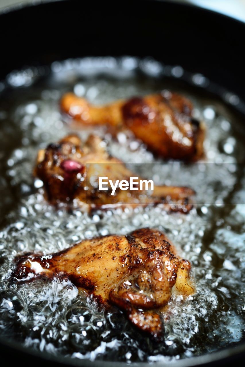 Close-up of chicken wings frying in cast iron skillet