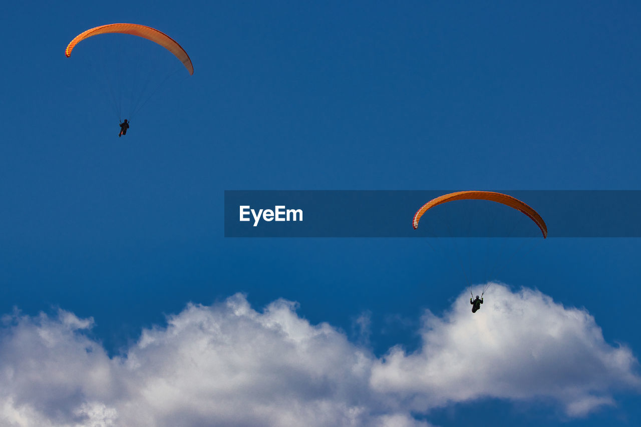 low angle view of man paragliding against sky