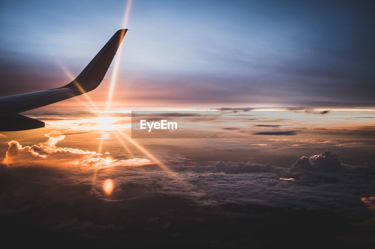 Cropped image of airplane flying against sky during sunset