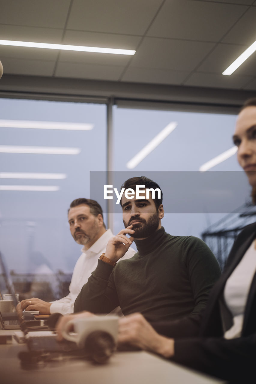 Ambitious businessman amidst male and female colleagues working late in office