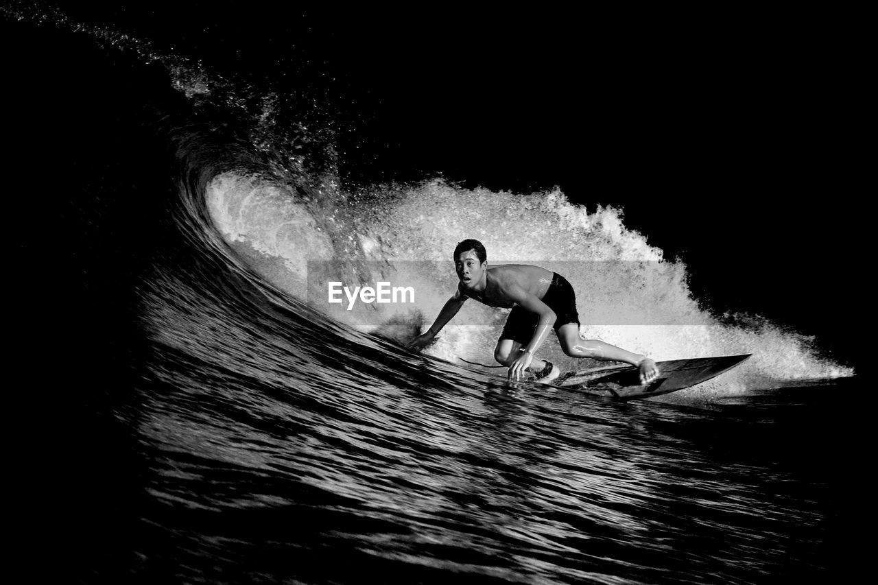 Full length of shirtless man surfing in sea