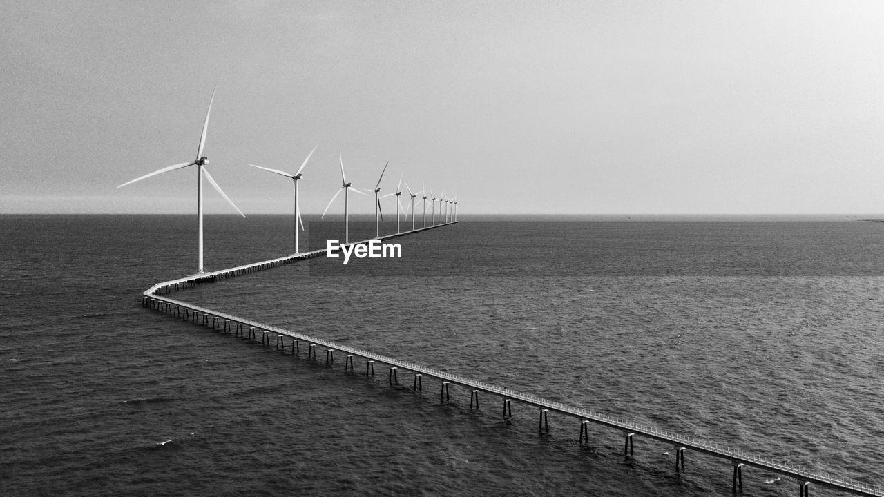 renewable energy, wind turbine, wind power, environmental conservation, turbine, alternative energy, power generation, environment, sky, water, sea, horizon, black and white, nature, horizon over water, windmill, wind farm, beauty in nature, monochrome, sustainable resources, monochrome photography, technology, wind, no people, electricity, scenics - nature, landscape, tranquility, day, outdoors, power in nature, land, social issues, seascape, tranquil scene, beach, environmental issues, copy space, power supply, coast, architecture, urban skyline