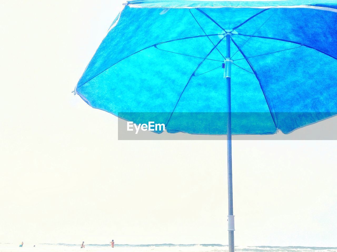 Blue umbrella on beach against clear sky