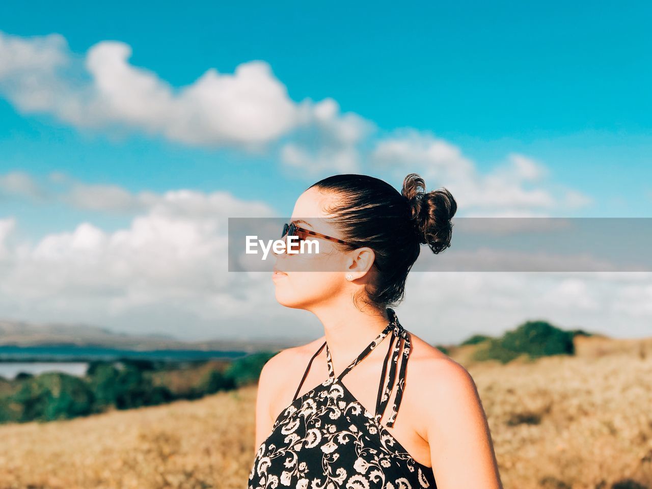 Young woman wearing sunglasses on field against sky