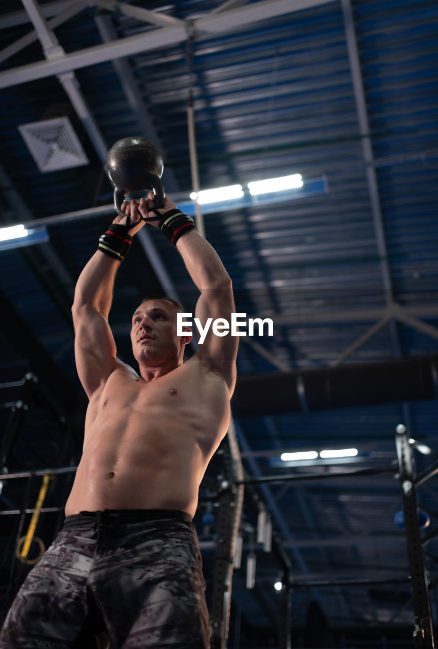 Powerful bodybuilder lifting kettlebell in gym