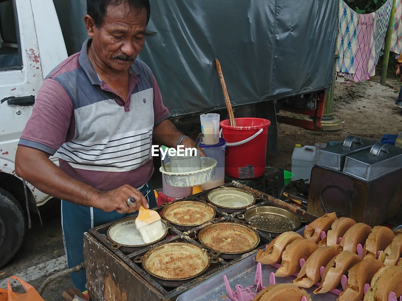 FULL LENGTH OF MAN STANDING BY MARKET STALL