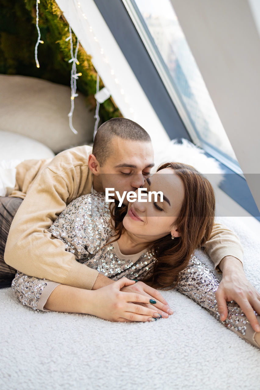 Portrait of smiling young couple lying on bed at home