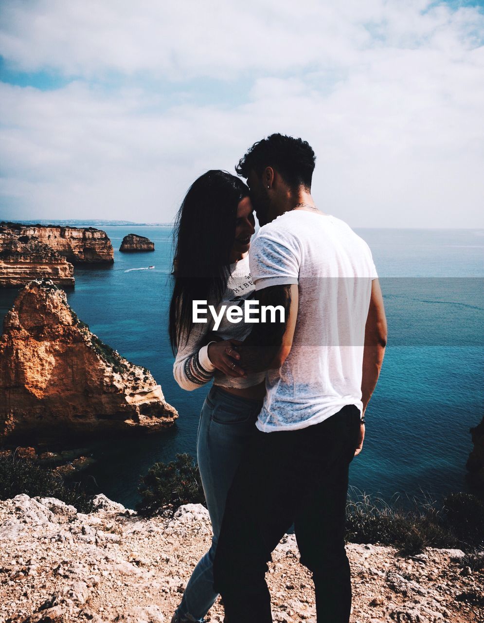 Rear view of couple standing at beach against sky