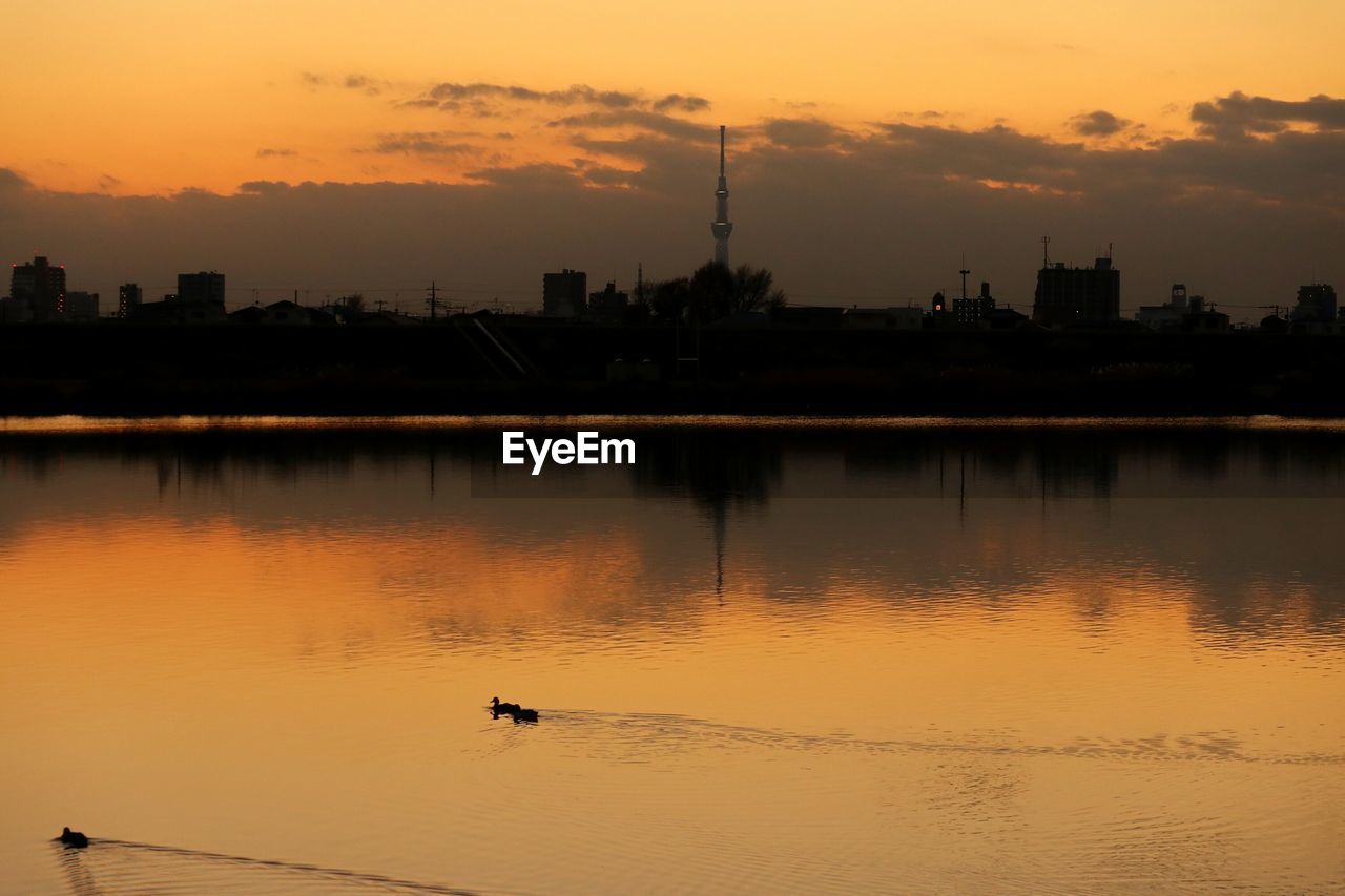 Scenic view of lake against cloudy sky during sunset