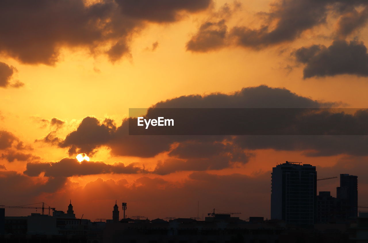 SILHOUETTE BUILDINGS AGAINST ORANGE SKY