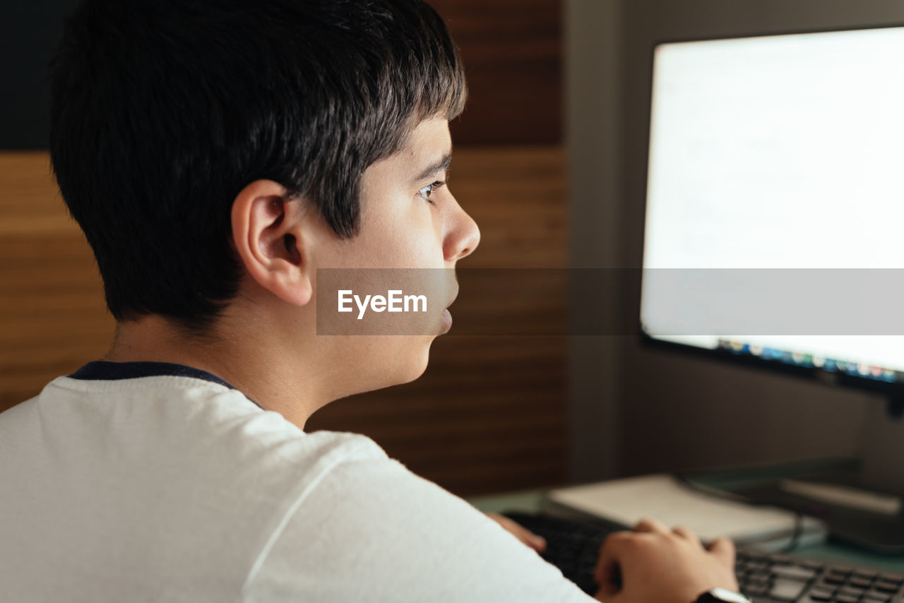 SIDE VIEW PORTRAIT OF BOY LOOKING AT CAMERA