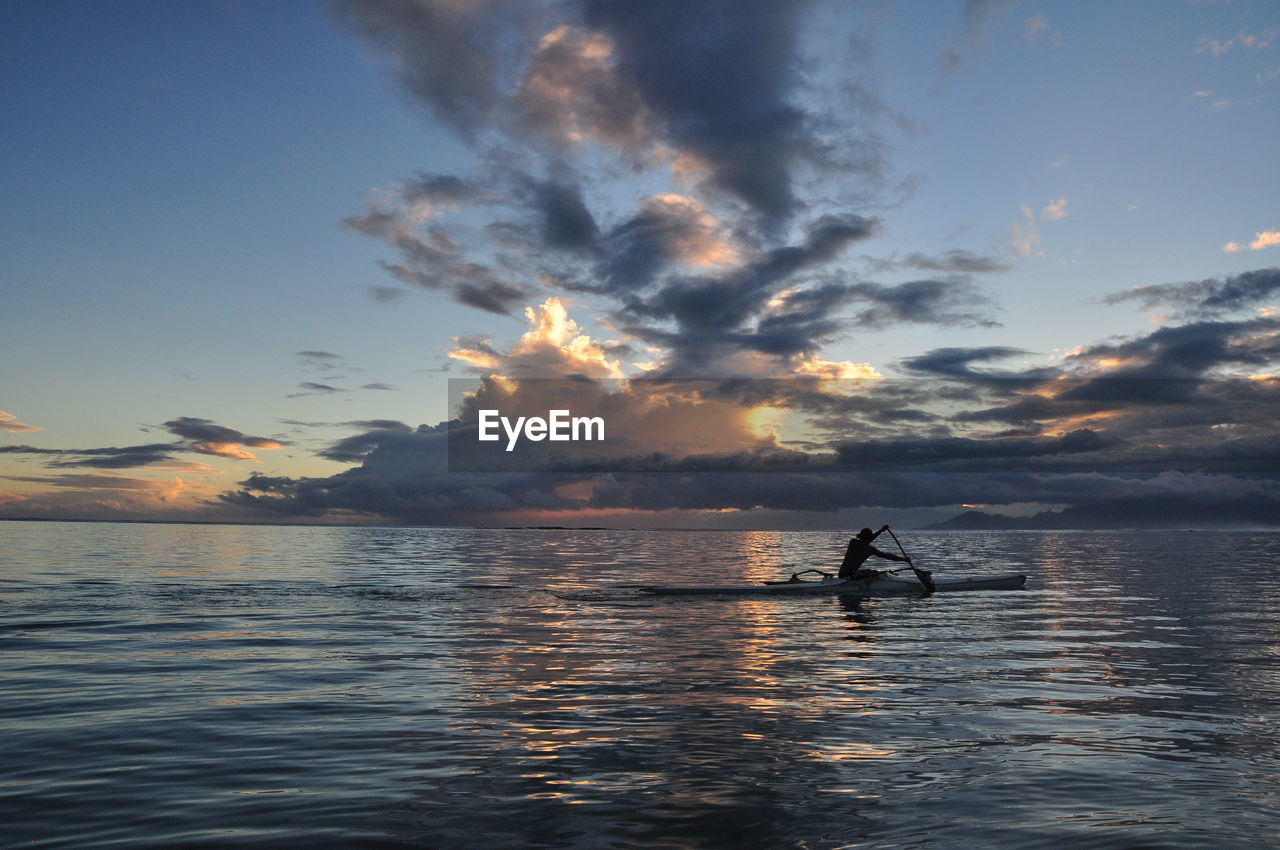 Silhouette person on boat in sea against sky during sunset