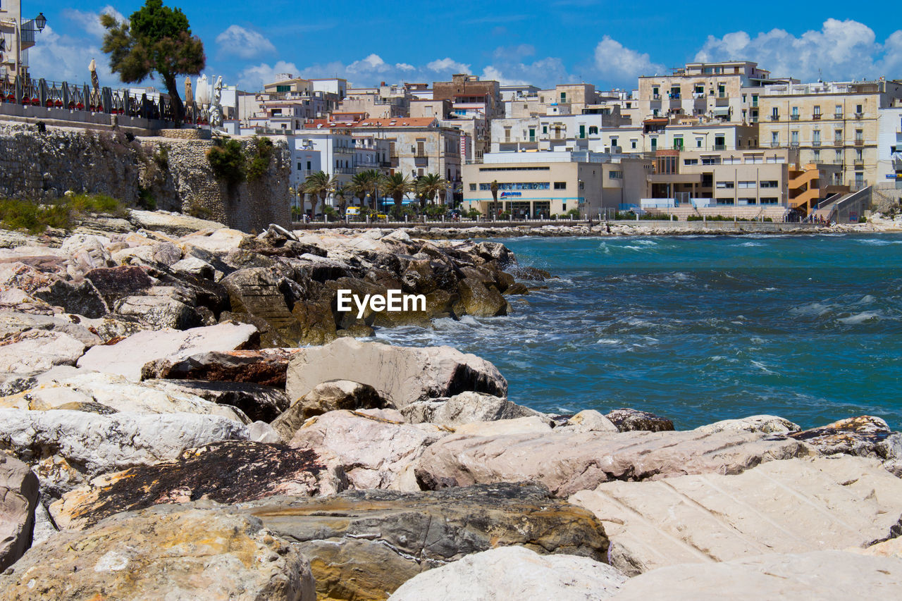 Buildings by sea against sky