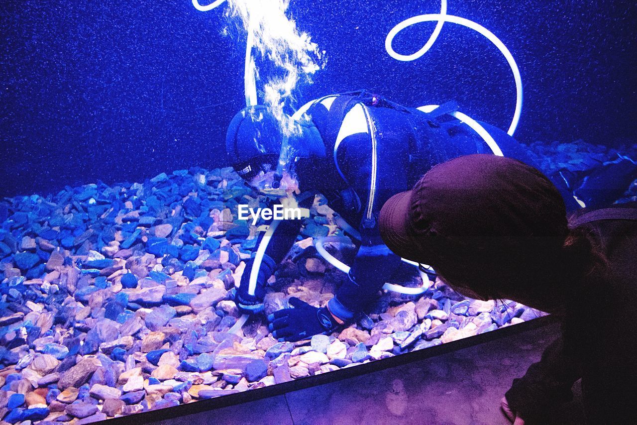 Woman looking at worker cleaning aquarium