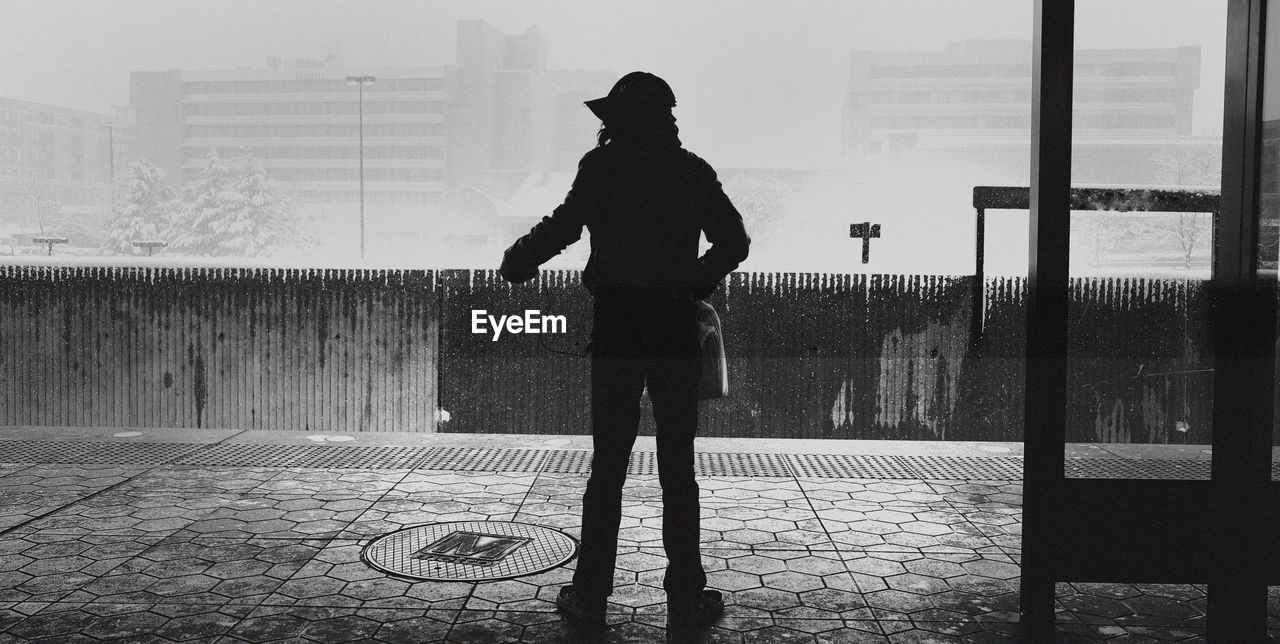 SILHOUETTE MAN STANDING AGAINST WALL