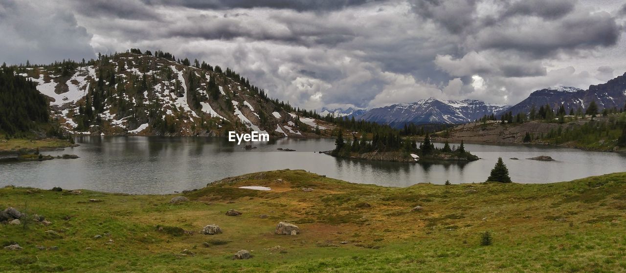 Scenic view of lake and mountains against cloudy sky