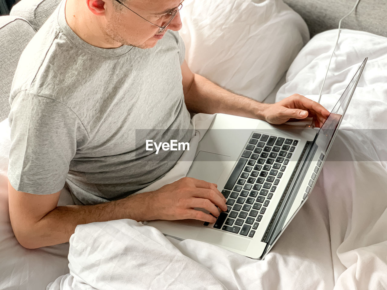 Middle aged man using laptop at home in bed vibes early morning working. freelancer, freelance job