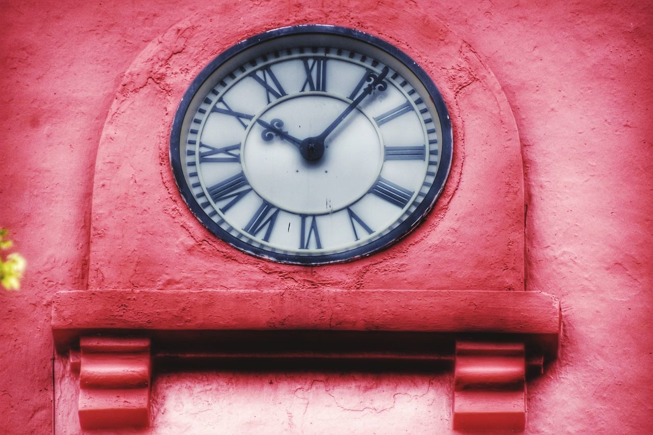 LOW ANGLE VIEW OF CLOCK AGAINST RED WALL