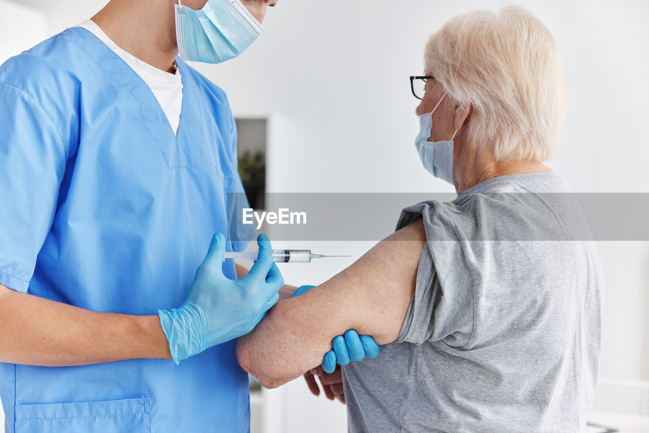 Midsection of doctor vaccinating patient at clinic