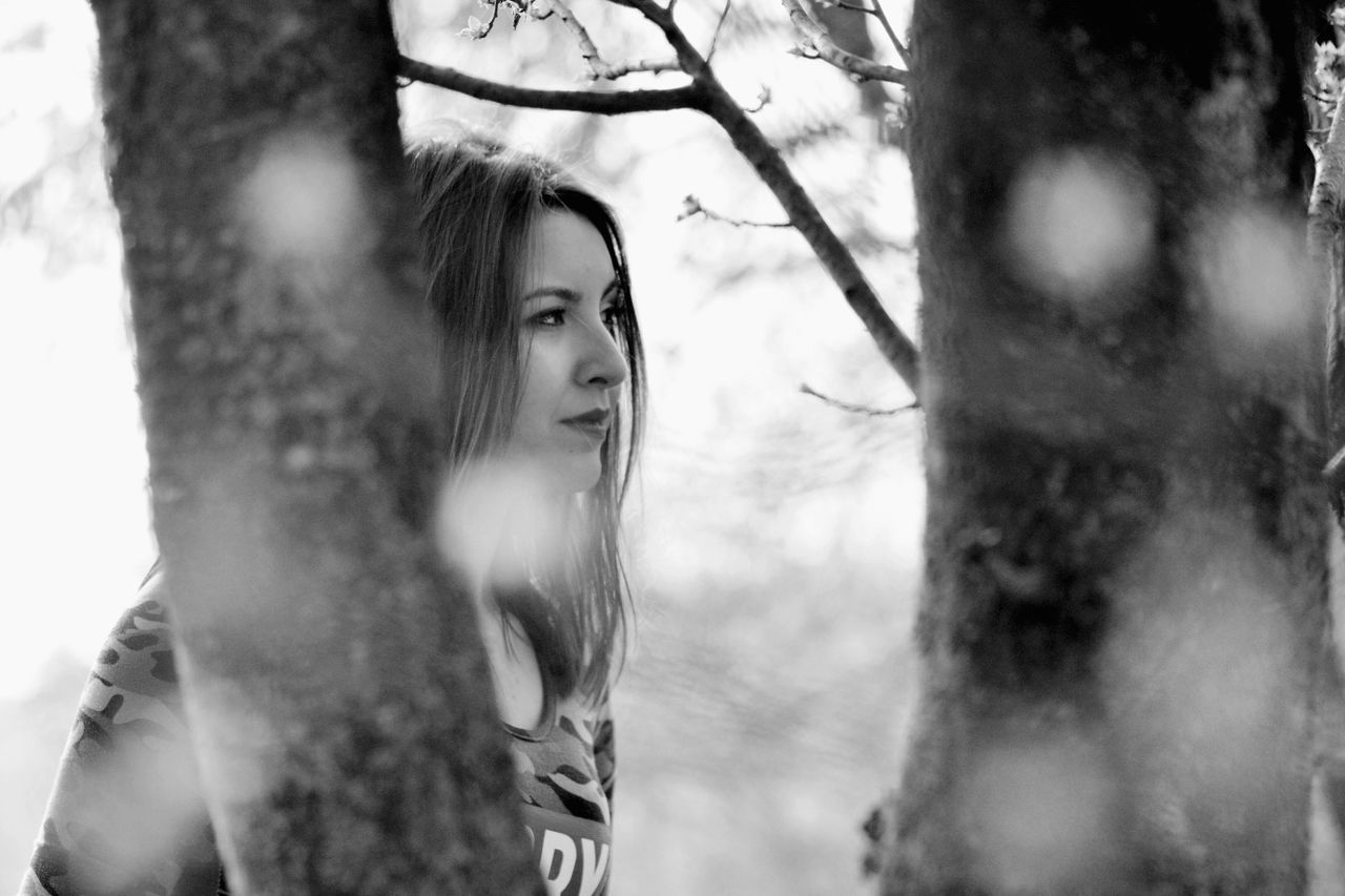 Close-up of young woman against tree trunk