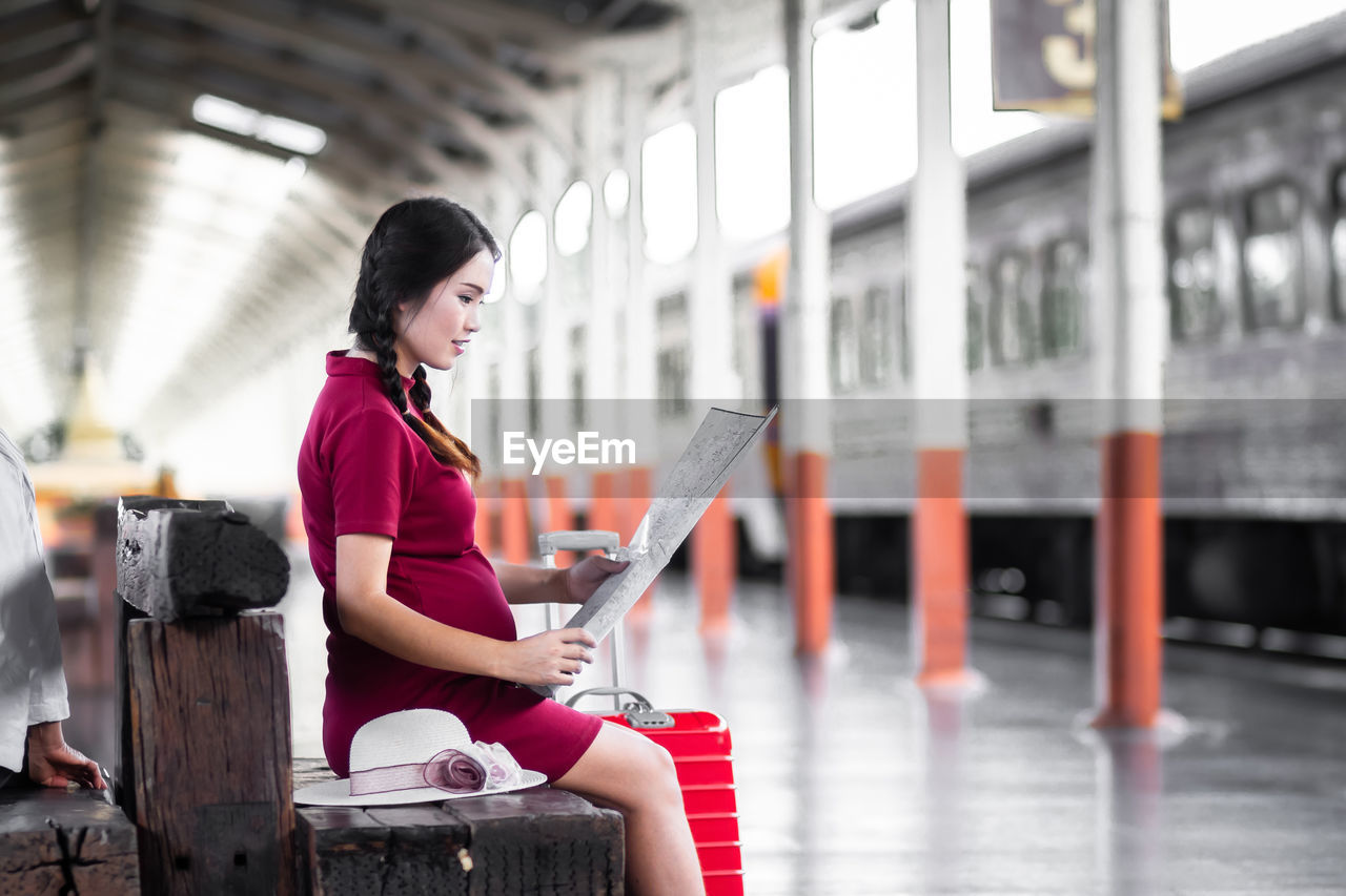 side view of man using mobile phone while standing on railroad station