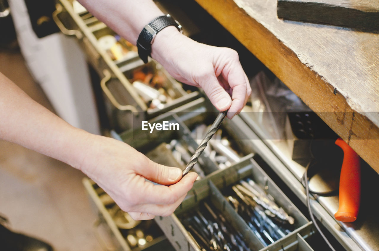 Cropped image of senior craftsperson holding drill bit in jewelry workshop