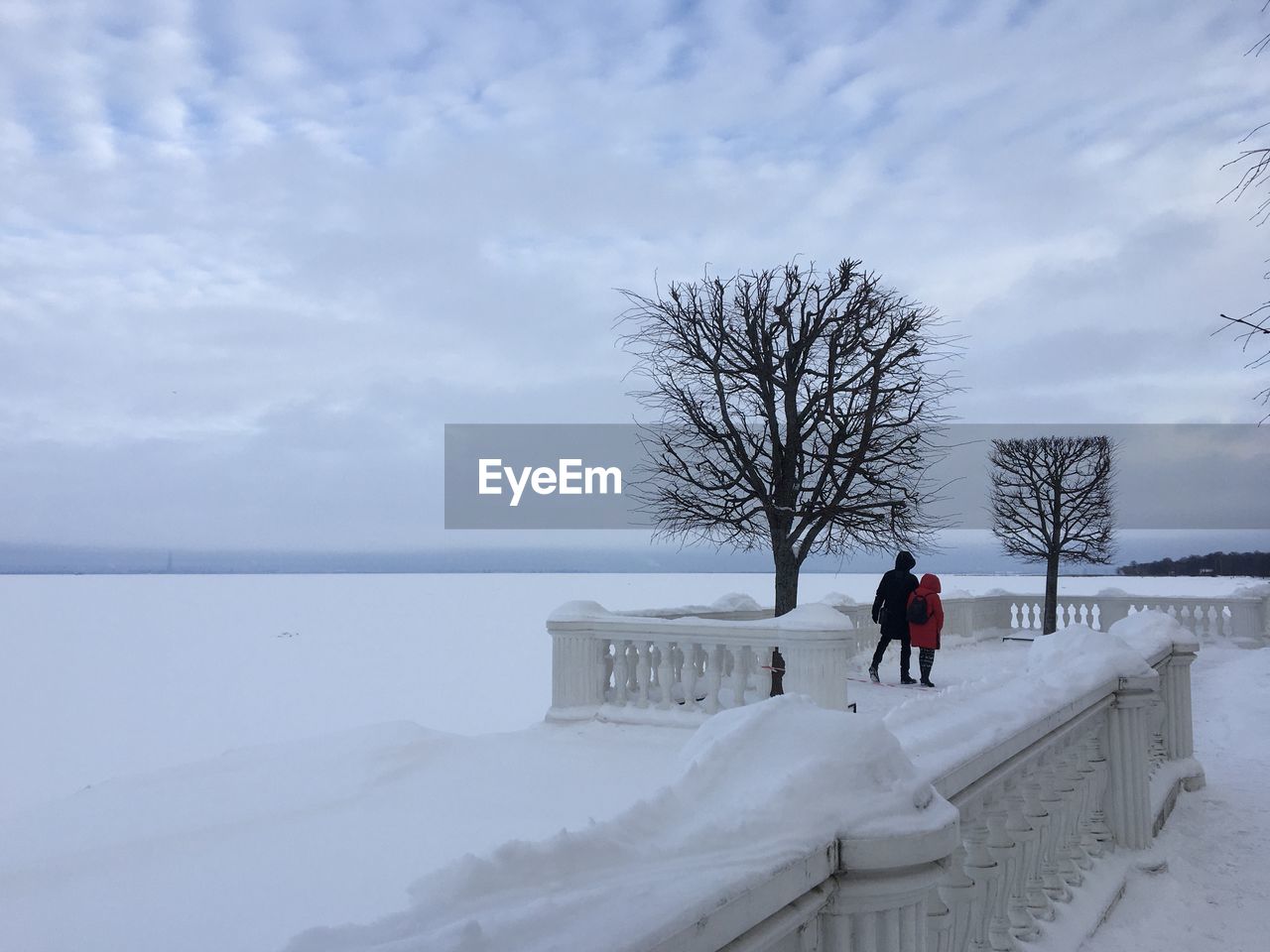 rear view of woman walking on snow covered landscape against sky