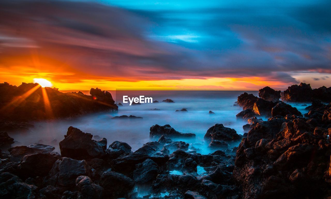 Scenic view of sea against dramatic sky during sunset