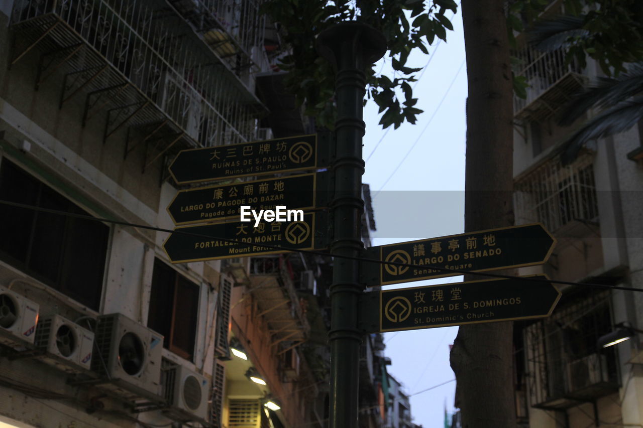 LOW ANGLE VIEW OF ROAD SIGN AGAINST CITY