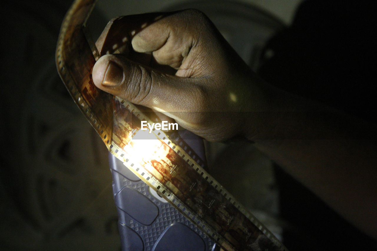 Cropped hand of man holding illuminated light bulb