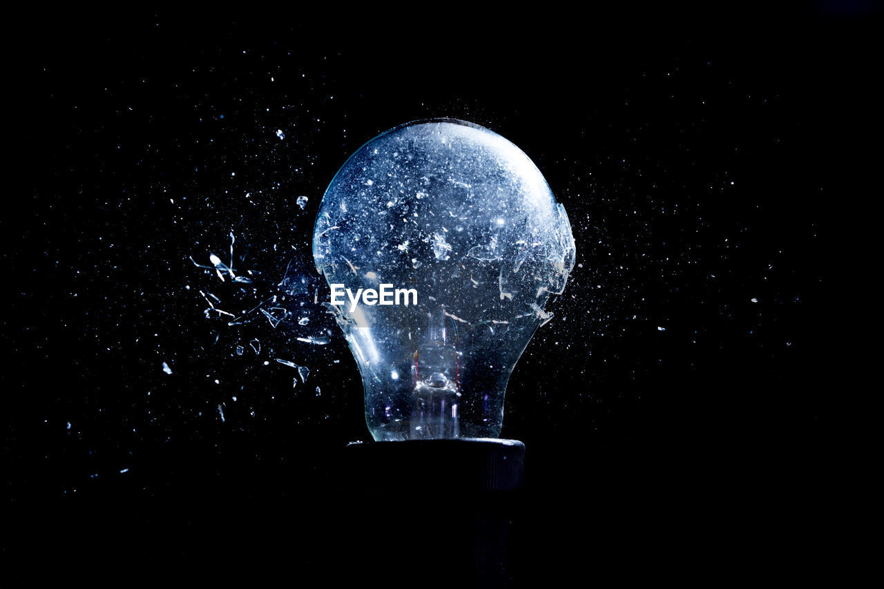 Close-up of damaged light bulb against black background