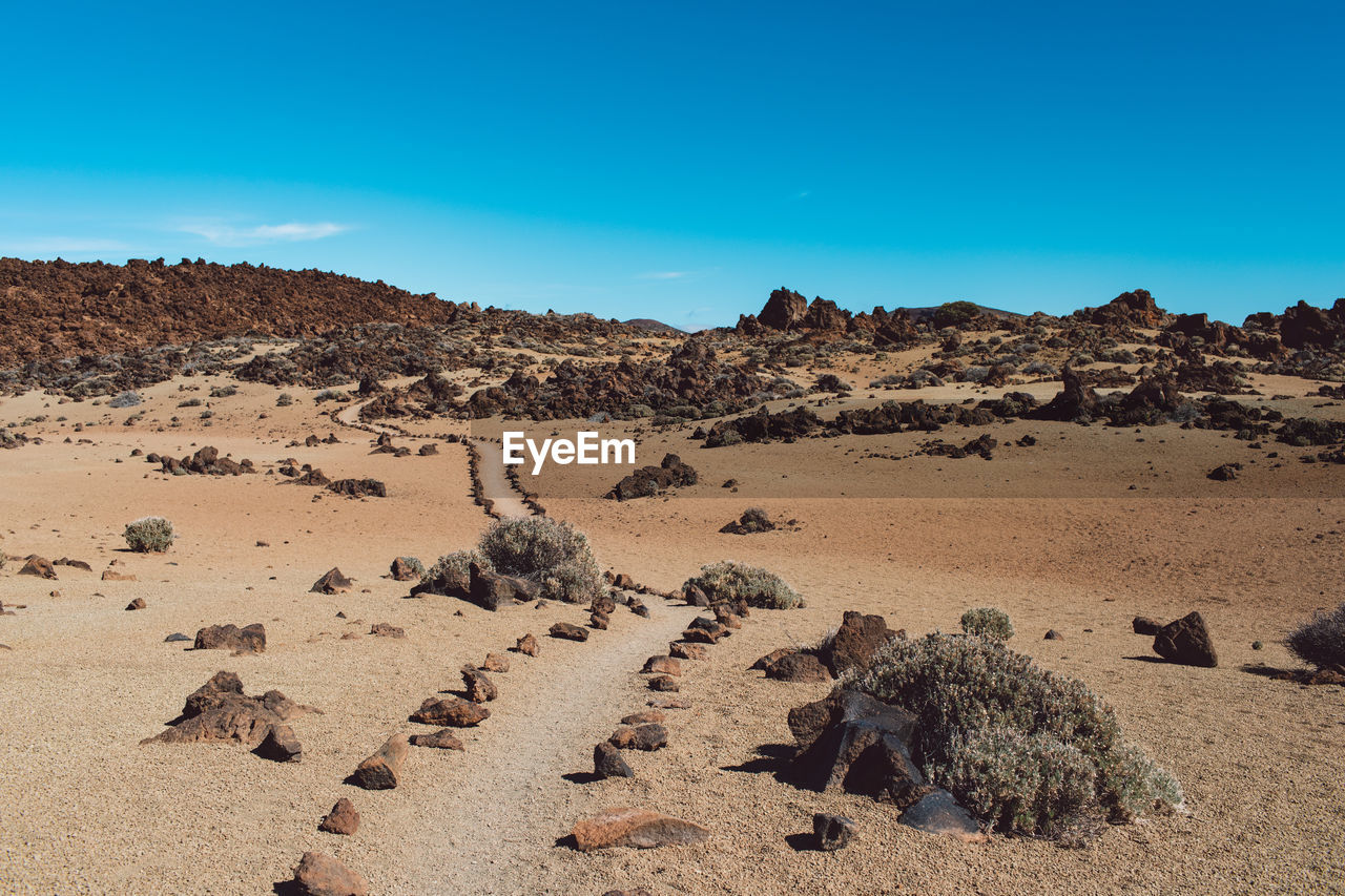 Scenic view of desert against blue sky