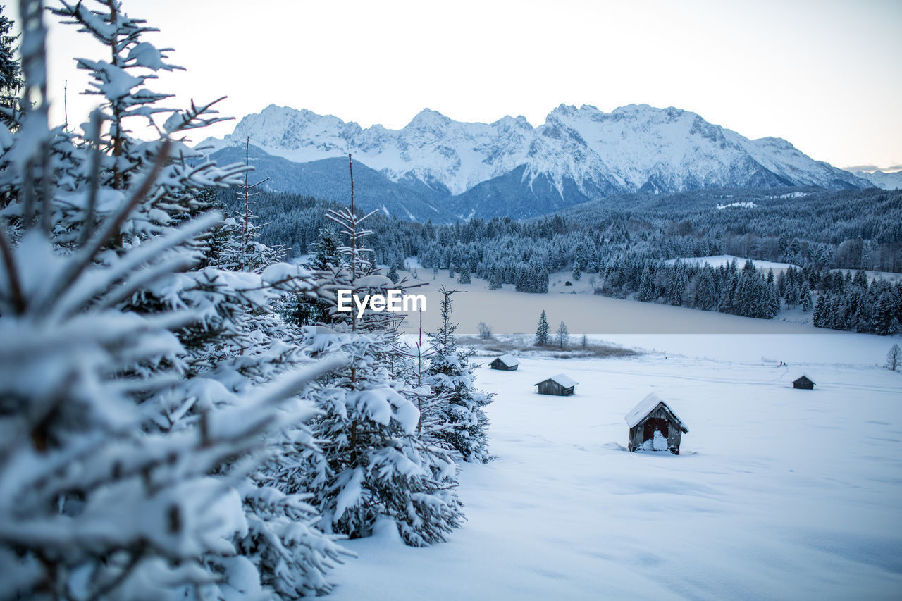 Scenic view of snow covered field and barn with mountains against sky, bavaria, germany.