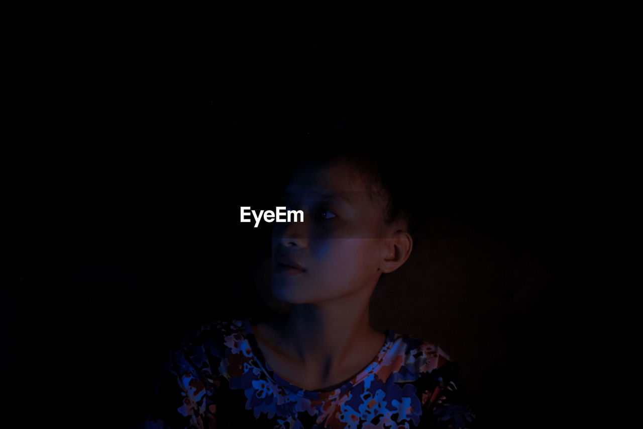 Portrait of girl looking away against black background