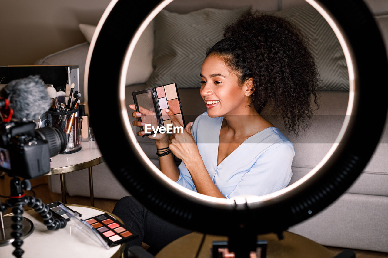 Young woman making video on make-up blog at home