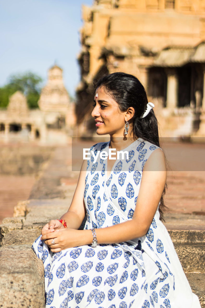 Young woman smiling while sitting at historic temple