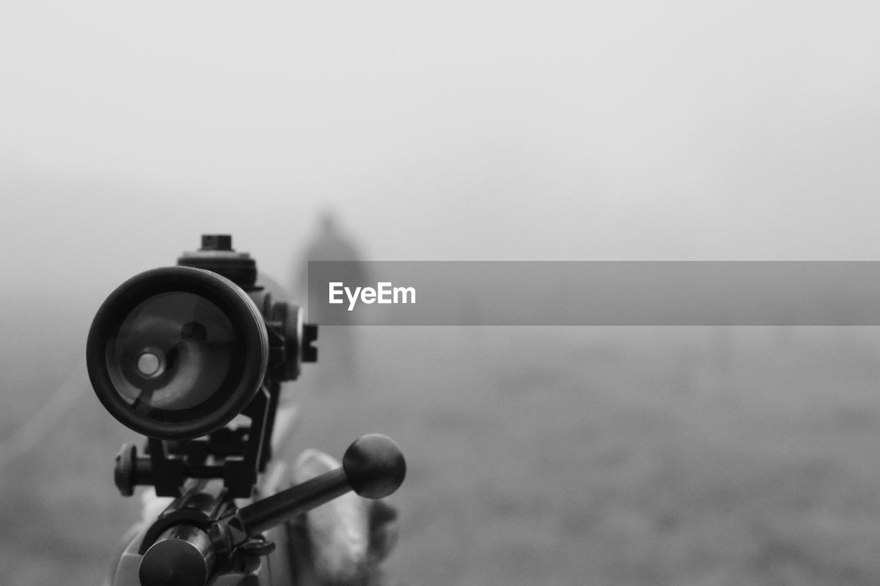 Close-up of sniper aiming at man on field during foggy weather