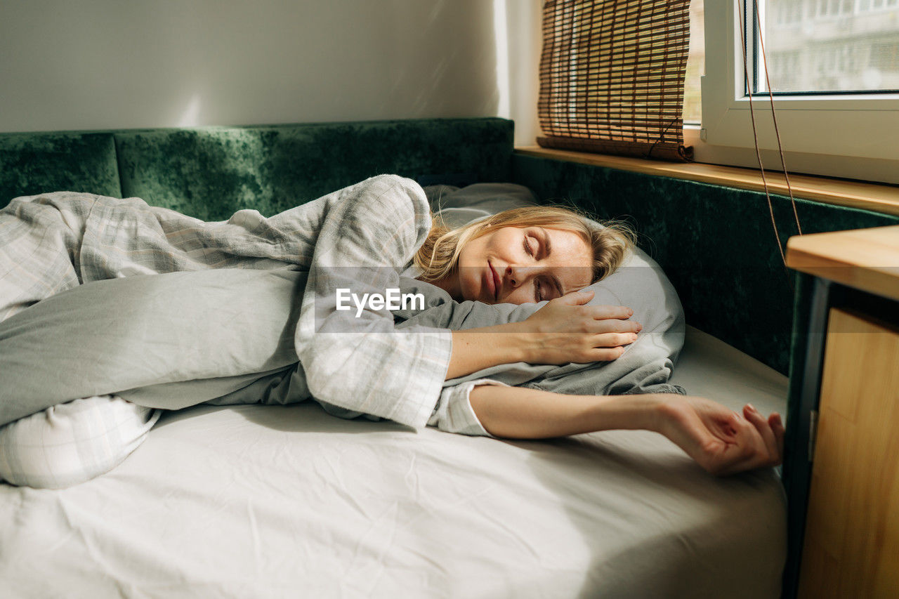 Young healthy caucasian woman sleeps soundly on the bed in the morning.