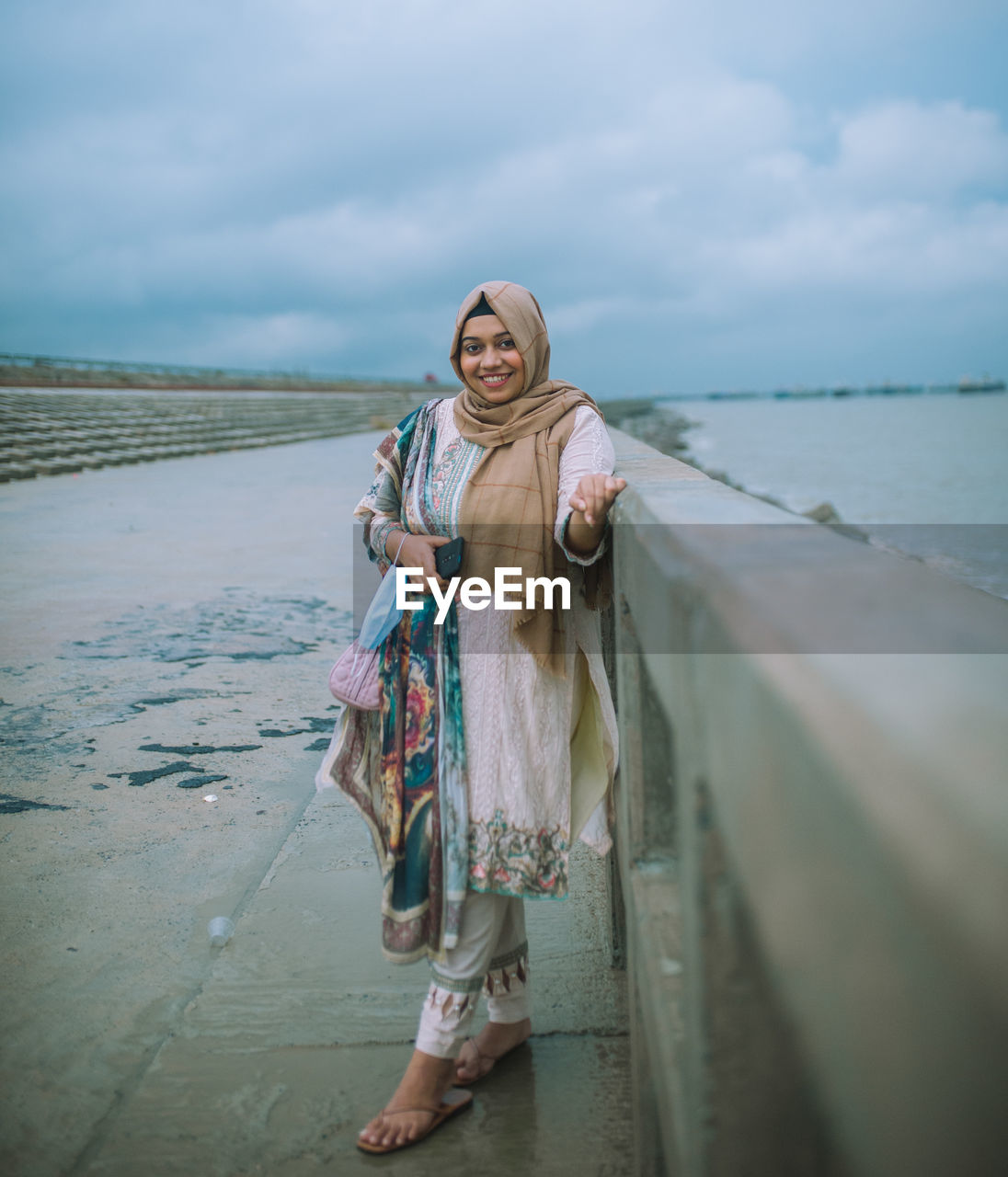 Woman standing at beach against sky