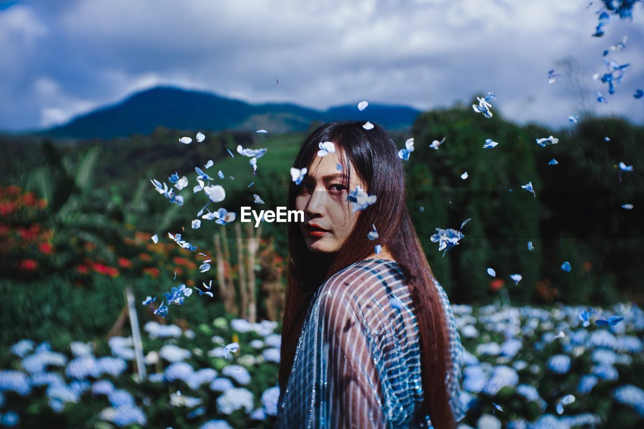 Portrait of young woman amidst flowers in park