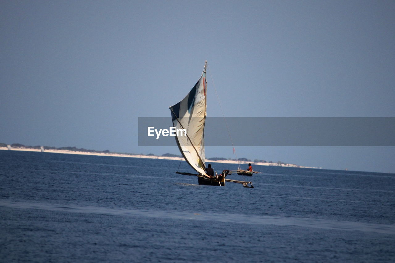 Sailboat sailing on sea against clear sky