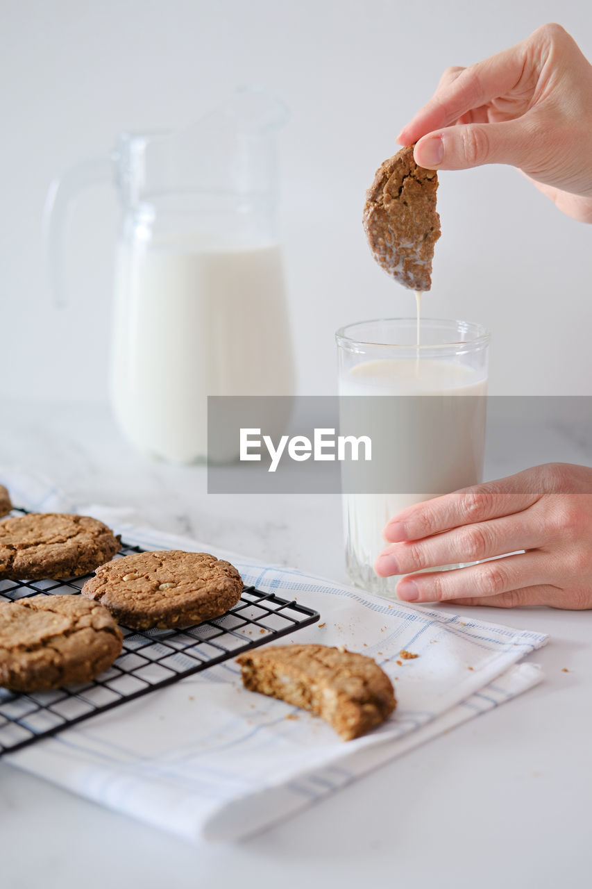 Woman's hand dipping homemade cookies into a glass of milk